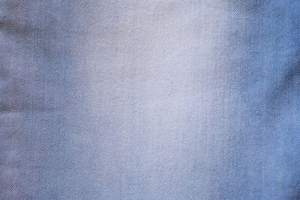 Denim fabric close up. Light blue jeans top view. Textile background, texture of jeans with frayed.  - Photo, Image
