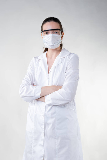 young female doctor sees patients, wearing a protective mask and glasses on her face - Photo, image
