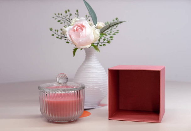 Pink scented candle in a glass candlestick and vase with a flower. - Photo, Image