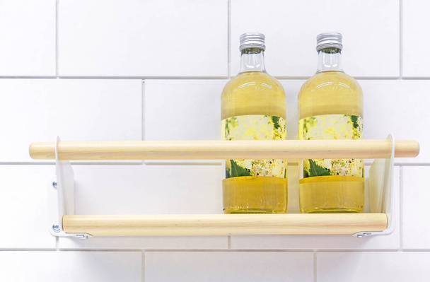 İki şişe sarı içecek, ahşap bir mutfak rafında.. - Fotoğraf, Görsel