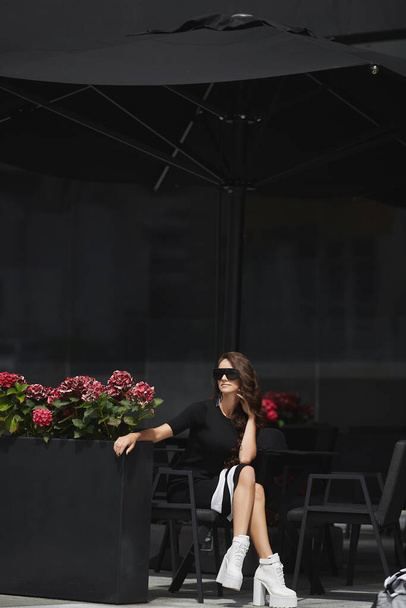 jong model meisje ontspannen buiten aan de cafe tafel op de stad straat - Foto, afbeelding