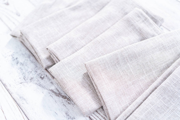 Vista de cerca de una servilleta de lino de color natural en una mesa blanca de madera. - Foto, Imagen