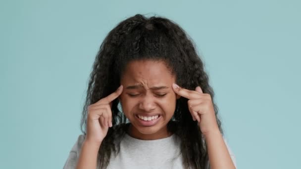 Akut baş ağrısı ya da migren krizinden muzdarip Afrikalı Amerikalı kız, masaj yapıyor ve yüzünü buruşturuyor. - Video, Çekim