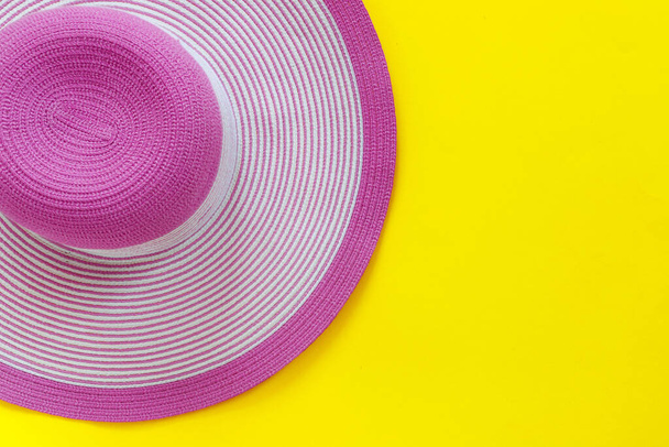 Fashionable pink straw hat on yellow paper background - Фото, изображение