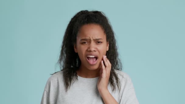 Citlivost zubů. Afričanky americká dospívající dívka trpící bolestí zubů, dotýkání zanícené tváře a šklebení - Záběry, video