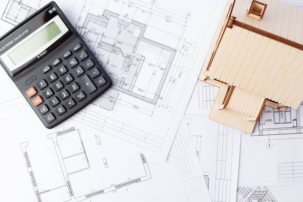 calculator and wooden house against the background of drawings - Photo, Image