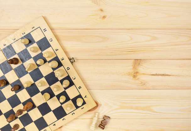 Шахматная доска и шахматные фигуры на деревянном фоне. Популярная логическая игра для логического мышления. - Фото, изображение