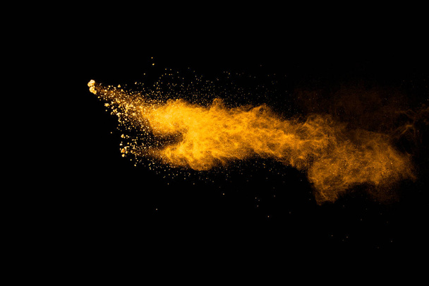 Abstrakte Explosion von orangefarbenem Staub auf schwarzem Hintergrund.. - Foto, Bild