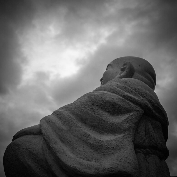 Στοχεύοντας τον Βούδα με δραματικά σύννεφα σε μαύρο και άσπρο. - Φωτογραφία, εικόνα