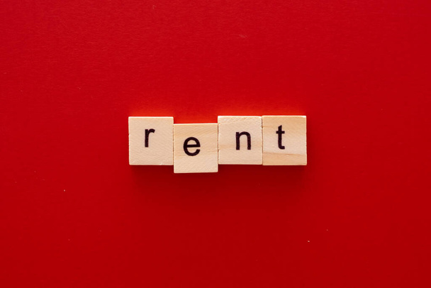 word RENT made of wooden letters on red background with copy space - Foto, imagen