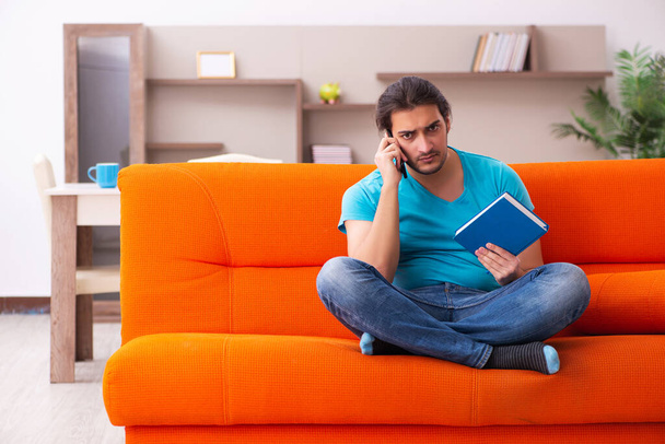 Junge männliche Studentin sitzt auf dem orangefarbenen Sofa - Foto, Bild