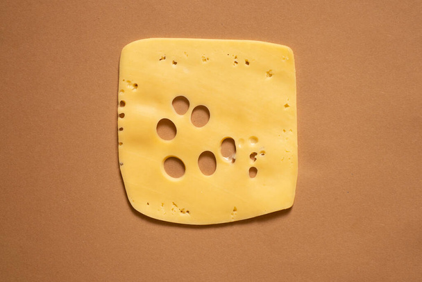 plak harde kaas met gaten op een geïsoleerde achtergrond, een stuk kaas - Foto, afbeelding