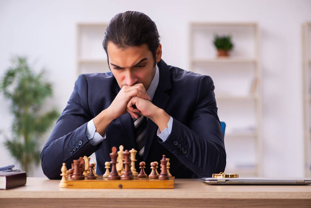 Joven empleado masculino jugando ajedrez en el lugar de trabajo - Foto, imagen