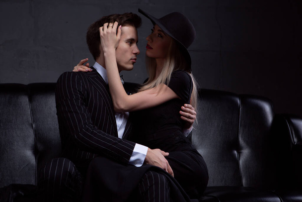 Elegant young couple in love embracing in tender passion sitting on a leather sofa - Photo, image