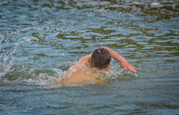 The guy is swimming in a crawl in a mountain river - Photo, Image