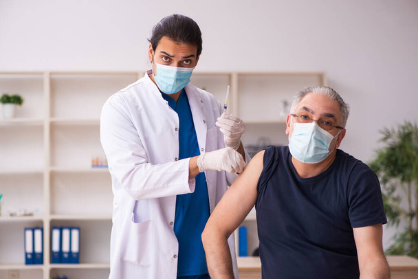 Vieil homme visitant jeune médecin dans le concept de vaccination covid-19 - Photo, image