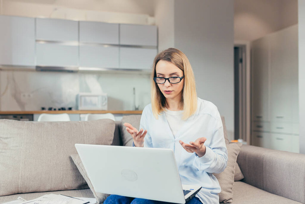 Beautiful woman holds online consultation using laptop sitting on sofa at home - Foto, Bild