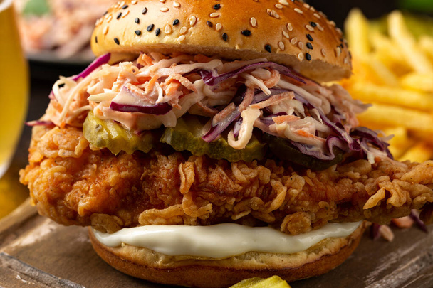 Hamburger di pollo fritto, sandwich con insalata di cavolo, cetriolini sottaceto, maionese e birra. Fast food. - Foto, immagini