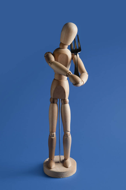Wooden mannequin with fork on color background - Photo, Image