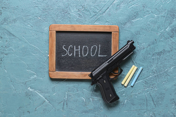 Pistol and chalkboard on color background. Concept of school shooting - Φωτογραφία, εικόνα