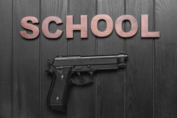 Pistola sobre fundo de madeira escura. Conceito de tiroteio escolar - Foto, Imagem