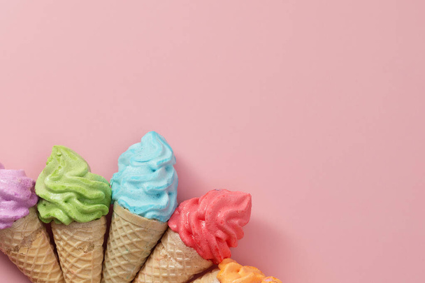 Verschiedene bunte Baiser-Eistüten auf rosa Hintergrund für süßes und erfrischendes Dessert-Konzept - Foto, Bild