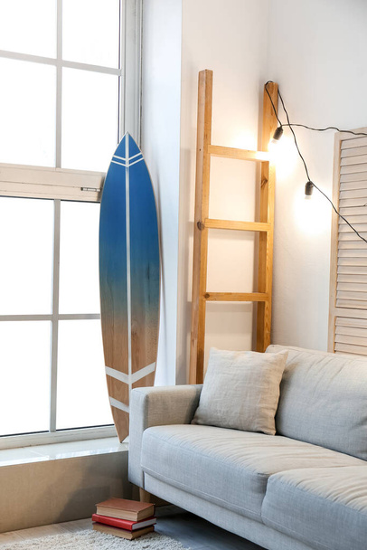 Belső tér modern stílusos szoba szörfdeszkával és kanapéval - Fotó, kép