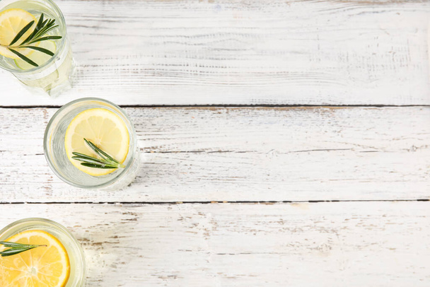 Glasses of healthy lemonade on light wooden background - Foto, imagen