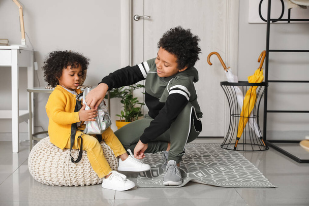 アフリカ系アメリカ人の男の子は家で妹の靴ひもを結ぶ - 写真・画像