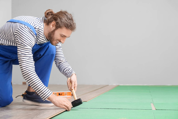 Carpenter installing laminate flooring in room - Photo, Image