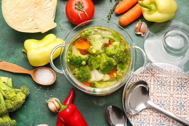 Стильний кулінарний горщик зі смачним супом та інгредієнтами на кольоровому фоні
 - Фото, зображення