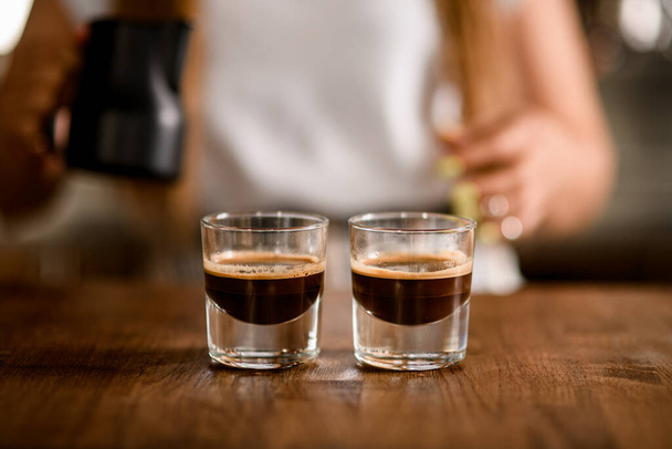two transparent glasses of freshly brewed espresso on wooden table - Valokuva, kuva