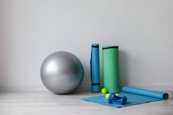 Set of sports equipment with fitness ball near light wall - Foto, Imagem