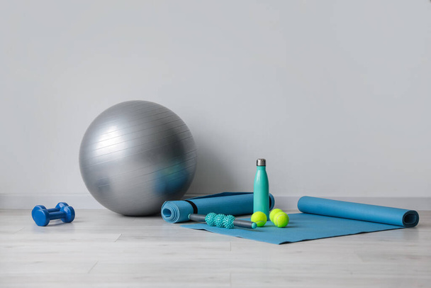 Set of sports equipment with fitness ball near light wall - 写真・画像