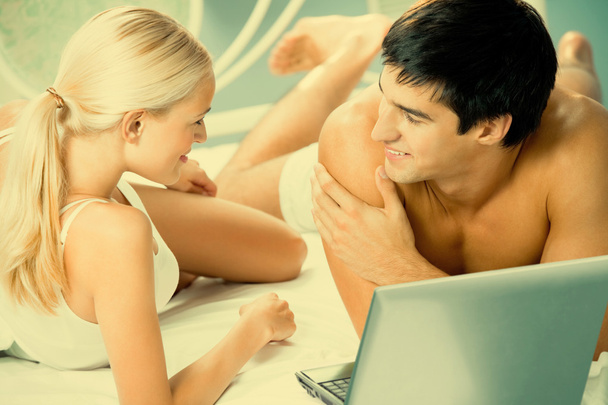 Young couple working with laptop at bedroom - Foto, imagen