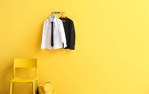 Hanger with stylish school uniform on color wall in room - 写真・画像