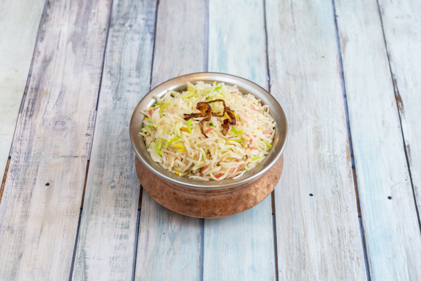 традиционная индийская металлическая миска с рисом плов в пакистанском ресторане на деревянном фоне - Фото, изображение