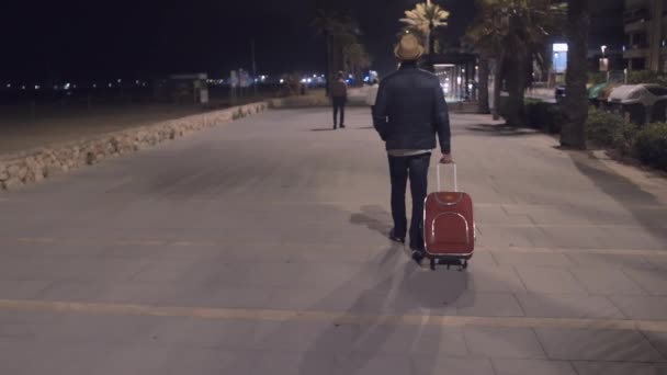 Турист з червоною валізою прийшов відпочити пізно вночі, прогулюється вздовж набережної, стежить за камерою
 - Кадри, відео