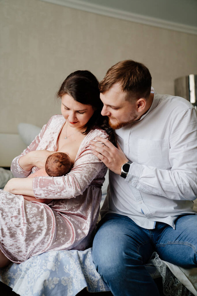 Happy family with toddler in bedroom. mom breastfeeds  - Photo, Image