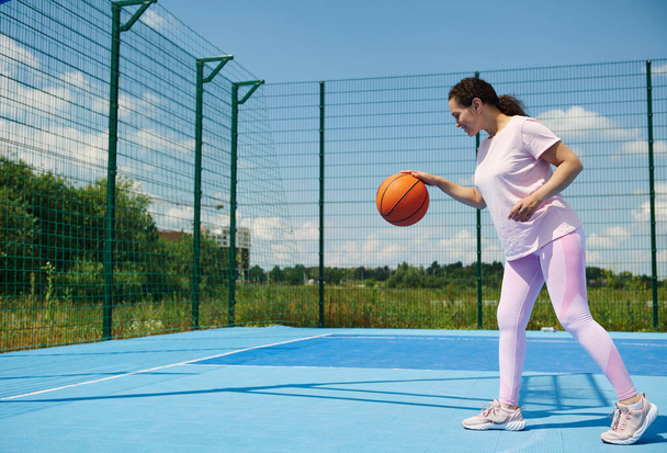 Giovane giocatore di basket femminile ripieno di una palla da basket sul campo - Foto, immagini