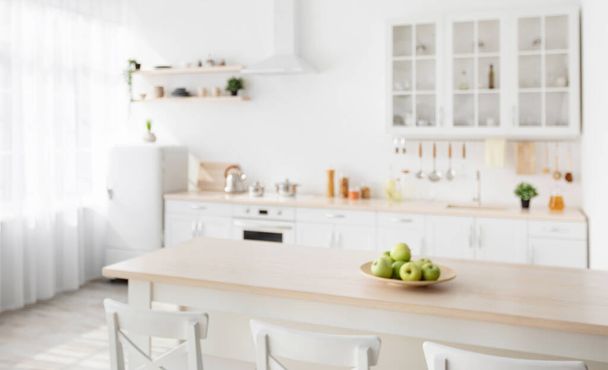 Σκανδιναβικό εσωτερικό της κουζίνας με ξύλινο νησί και λευκές καρέκλες γύρω από το ξενοδοχείο, σκεύη και πιάτα σε έπιπλα κουζίνας - Φωτογραφία, εικόνα