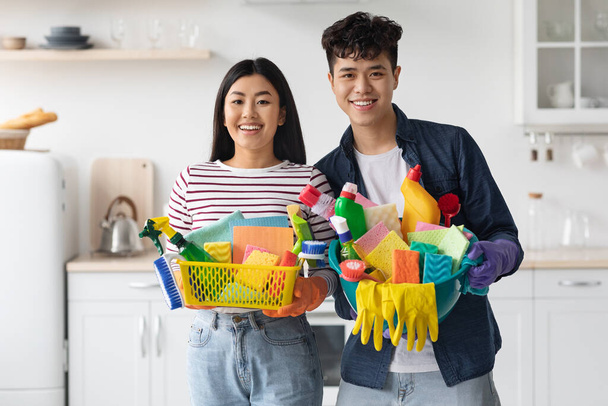Портрет улыбающихся азиатских домовладельцев с чистящими средствами - Фото, изображение