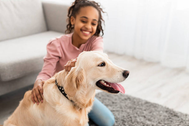 Fiatal fekete lány szórakozás kutyával otthon - Fotó, kép