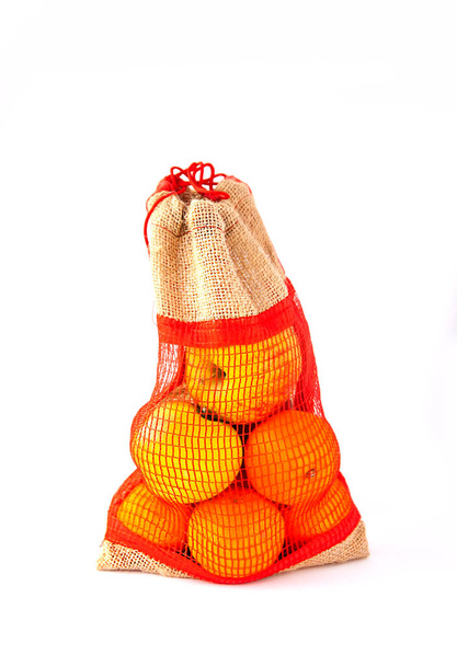 Beyaz arka planda çuval bezi içinde taze portakal meyveleri.. - Fotoğraf, Görsel