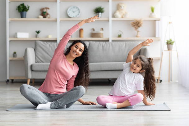 Atlético mãe e filha sentado no tapete de fitness, exercendo - Foto, Imagem