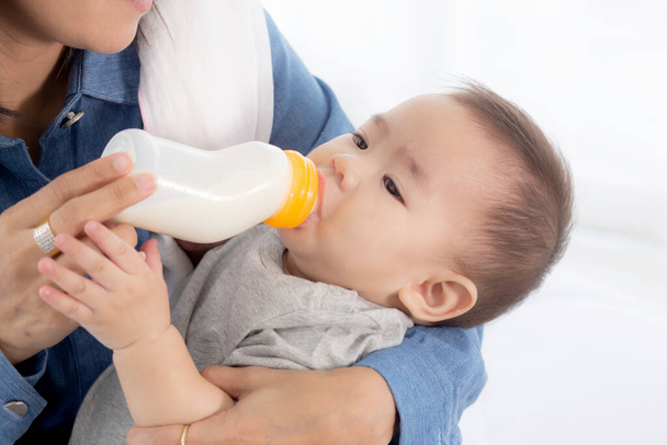 Mladá asijská matka objímání a krmení holčička s lahví mléka doma, novorozenec nevinnost pití s maminkou spokojeni, vztah a sblížení maminky a dítěte, rodinný koncept. - Fotografie, Obrázek