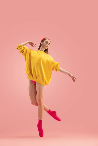 Portret van jong mooi meisje, vrouwelijke balletdanseres training geïsoleerd over roze achtergrond. - Foto, afbeelding