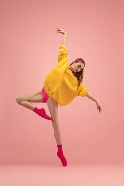 Slim tender young beautiful girl, female ballet dancer dancing isolated over pink background. - Fotografie, Obrázek