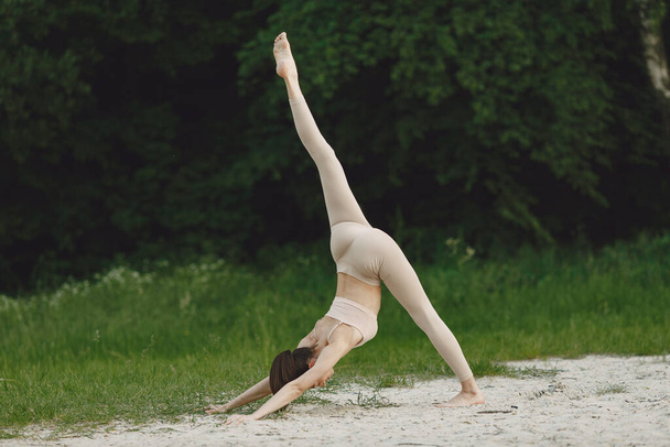 Woman practicing advanced yoga in a beach - Foto, Bild