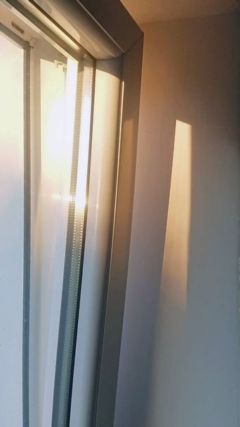 το βράδυ ο ήλιος λάμπει μέσα από ένα πλαστικό παράθυρο στο δωμάτιο - Φωτογραφία, εικόνα